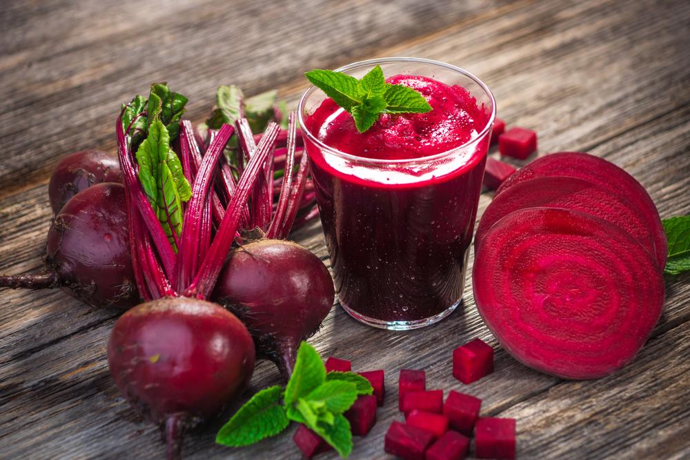 Beetroots and beetroot juice on a wooden table.