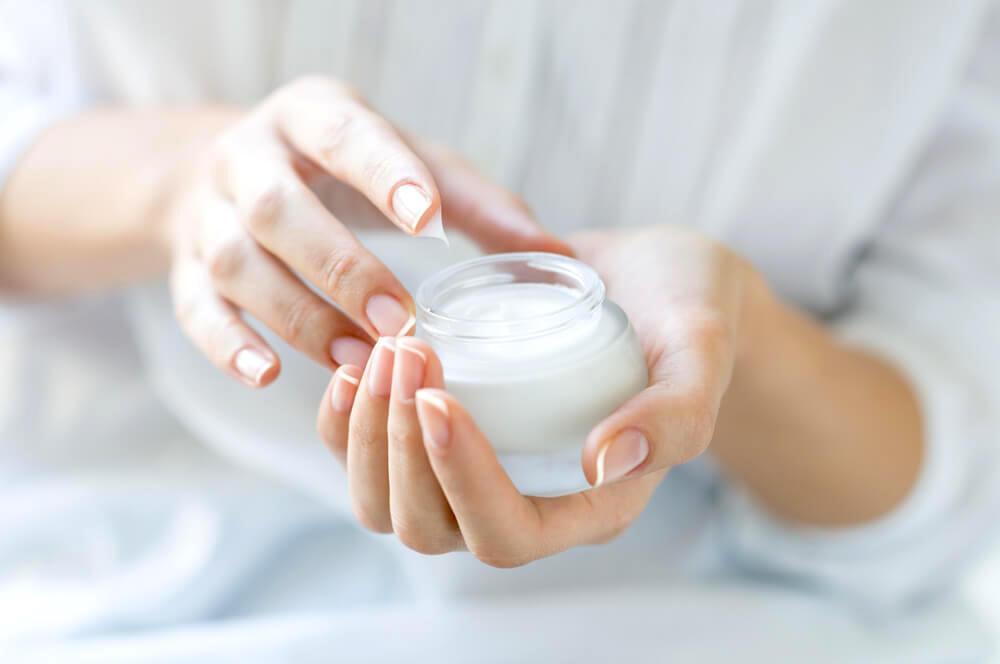 Woman's fingers dipping into moisturizer