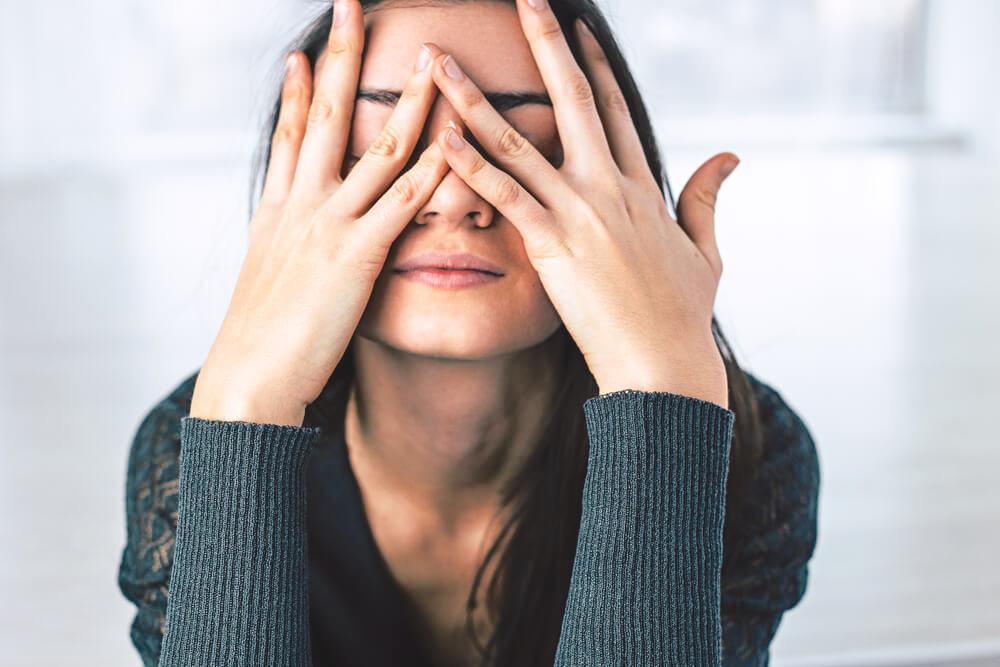 Stressed woman covering her face with her hands