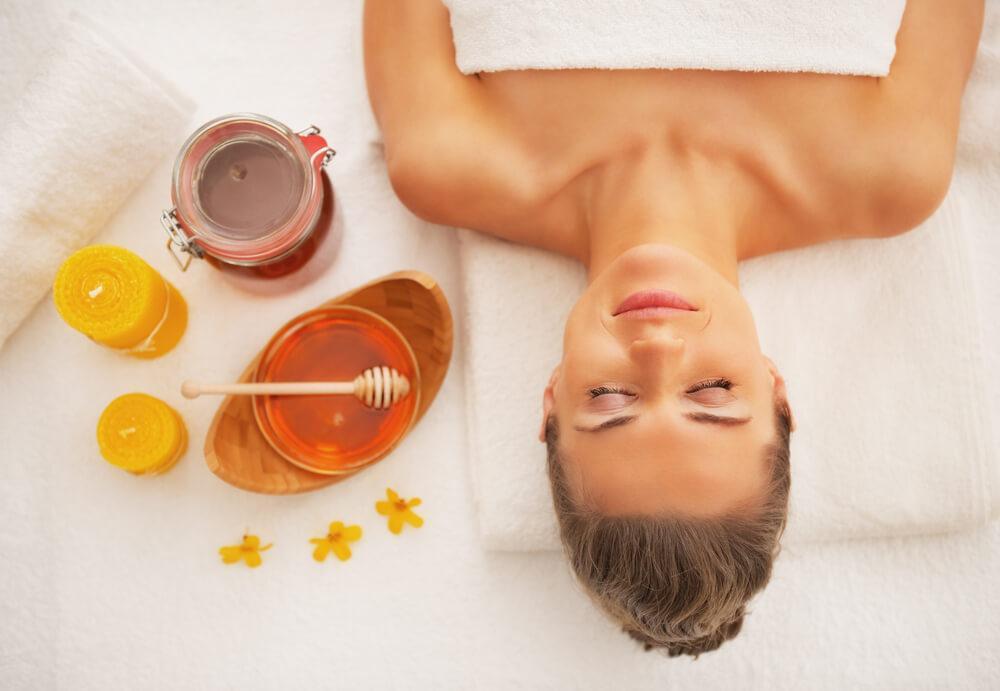 Woman lying down in spa with honey next to her