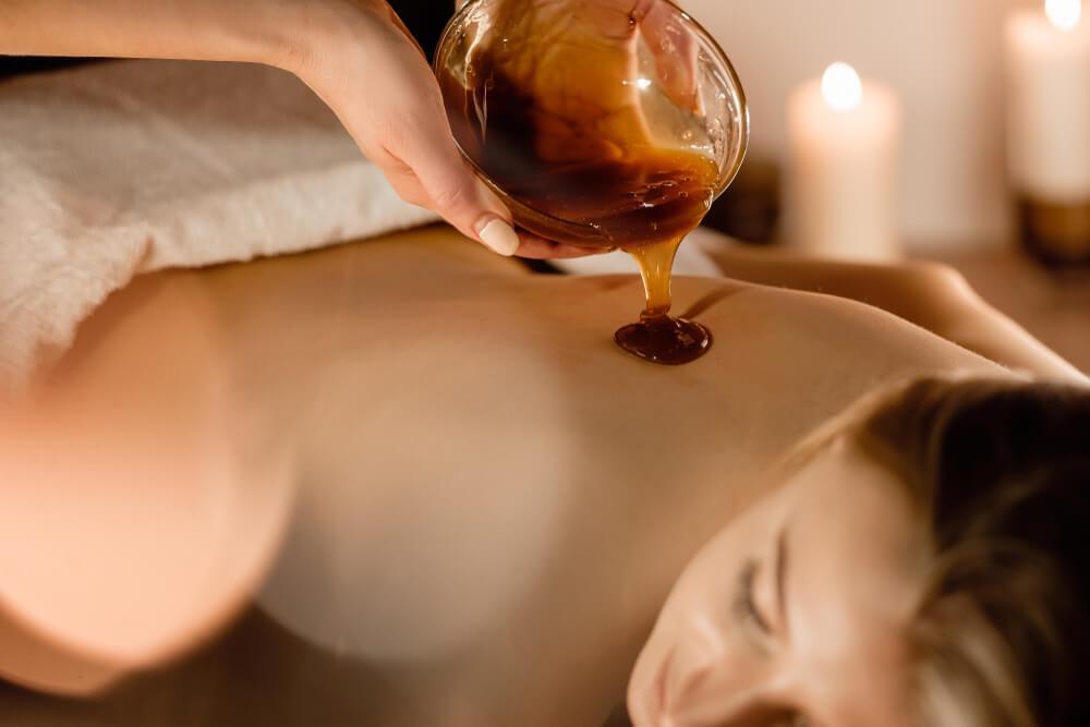 Spa treatment with honey pouring on woman's back