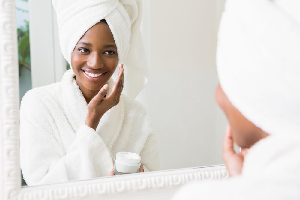 Woman in front of mirror applying face cream