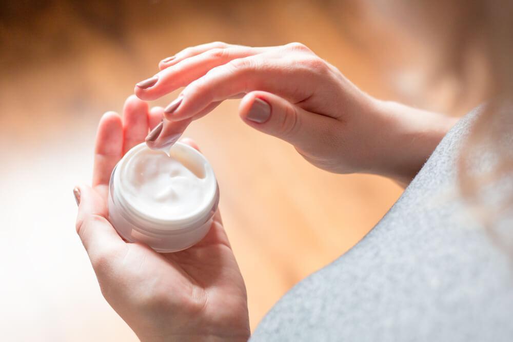 Hand in jar of face cream