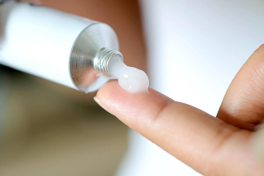 Hand squeezing tube of cream onto finger