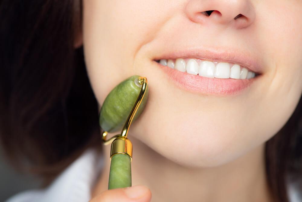 Woman using jade roller on face