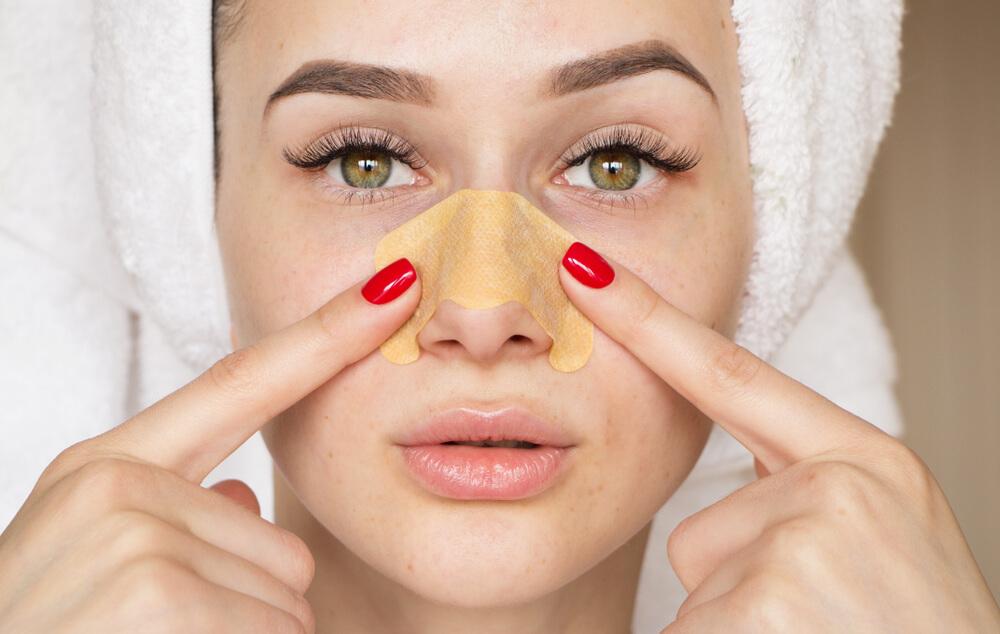 Woman using pore strips on nose