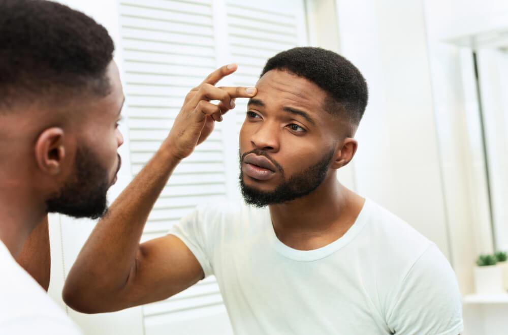 Man looking at wrinkles in mirror