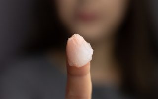Woman holding up finger with petroleum jelly for slugging
